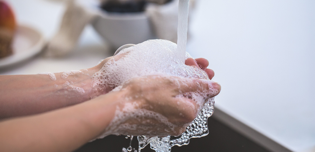Bild på ett par händer som tvättas under en vattenkran med rikligt tvålbubbel