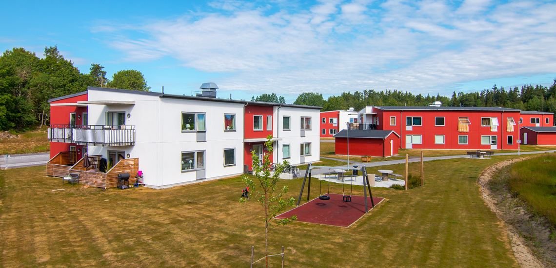 Vita och röda hus i grönområde med lekpark.