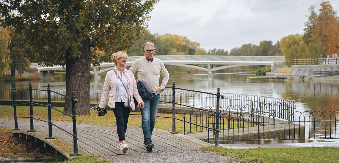 Ett äldre par promenerar på en bro över Eskilstunaån.