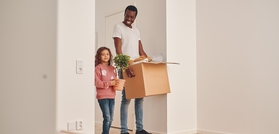 Bild på en pappa och dotter som flyttar lådor i en tom lägenhet.