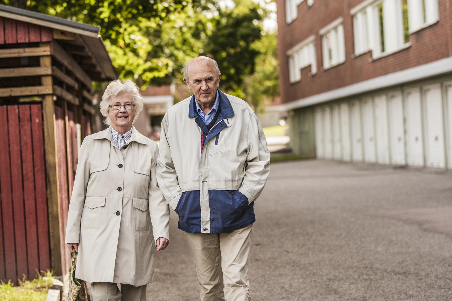 Ett äldre par promenerar i ett bostadsområde.