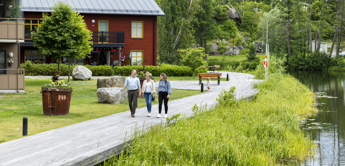 tre personer på promenad längs ån