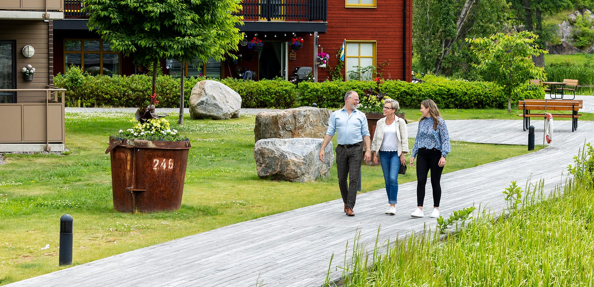 Två kvinnor och en man promenerar längs ån i Torshälla en sommardag.