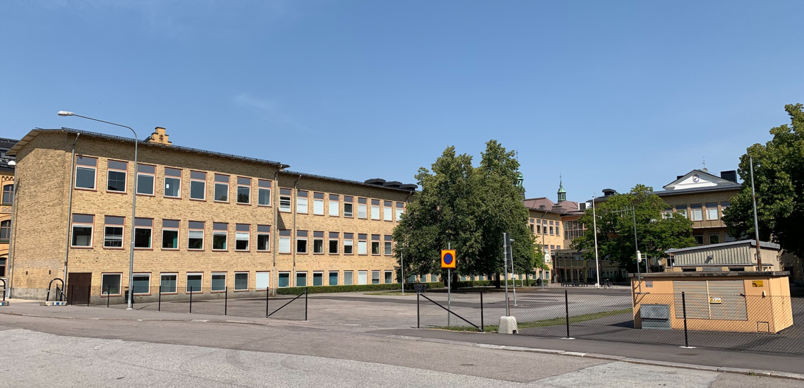 Skolbyggnad i ljust tegel samt skolgård