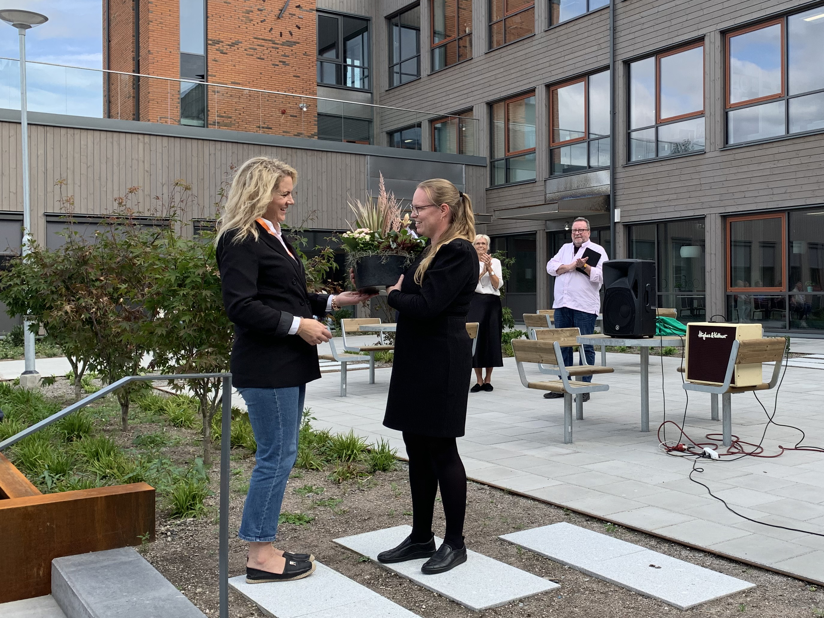 Kfasts projektchef överlämnar blomma till skolans rektor på skolgården.