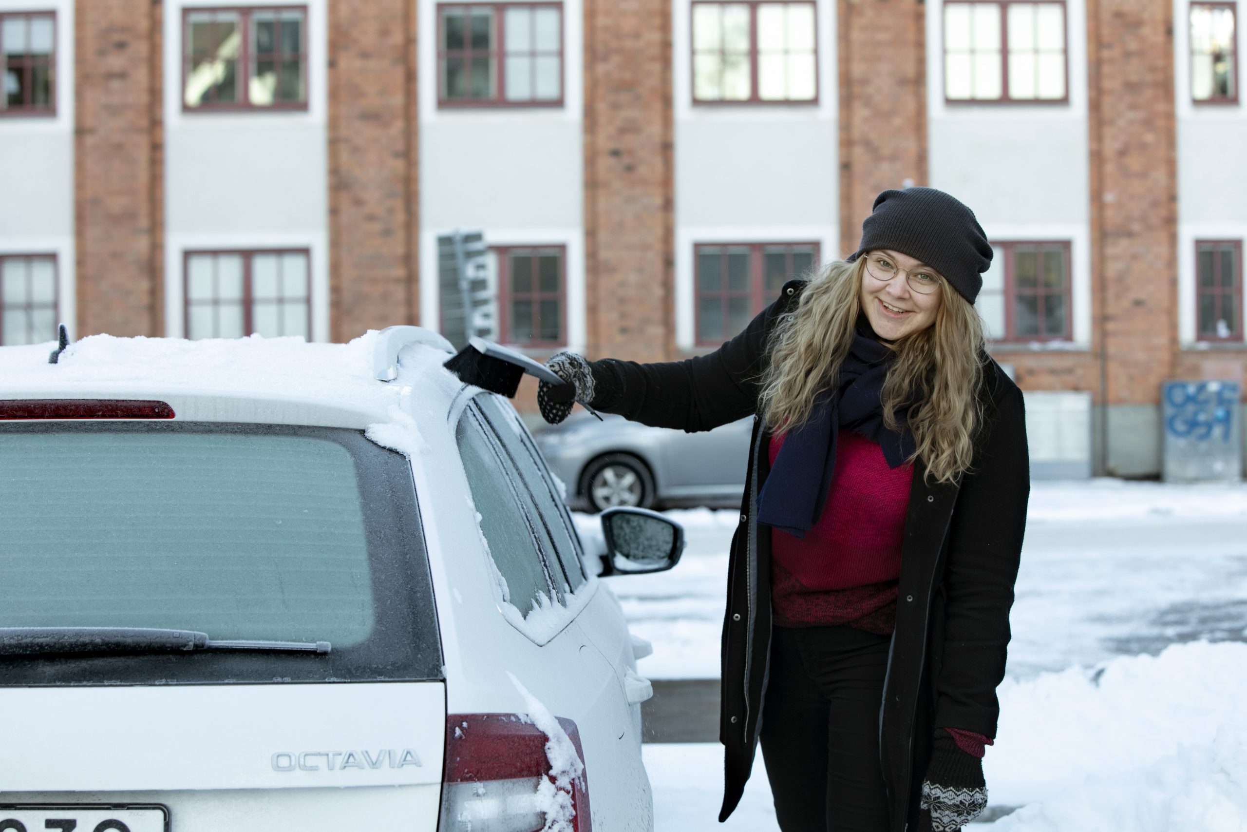 Kvinna borstar bort snö från biltaket