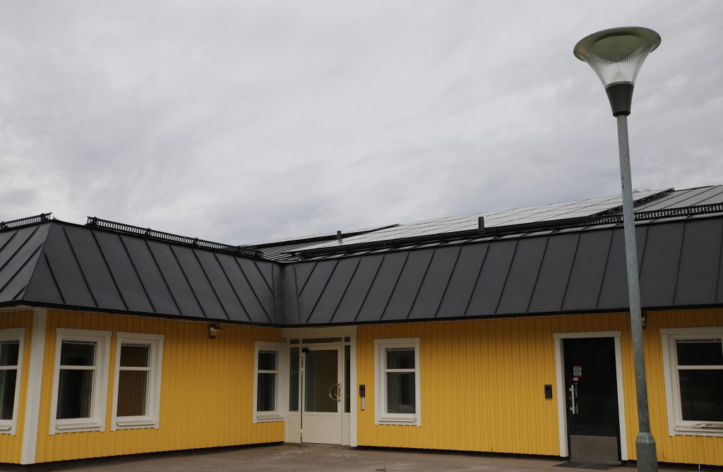Gul byggnad med solceller på taket. 