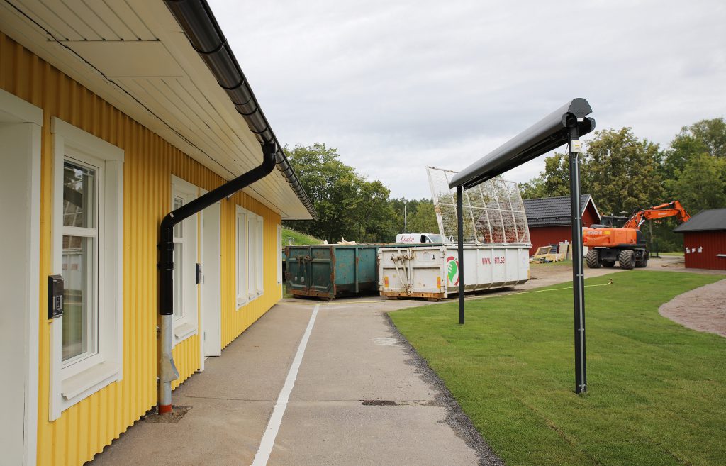 Gul byggnad med två stora containers i bakgrunden. 