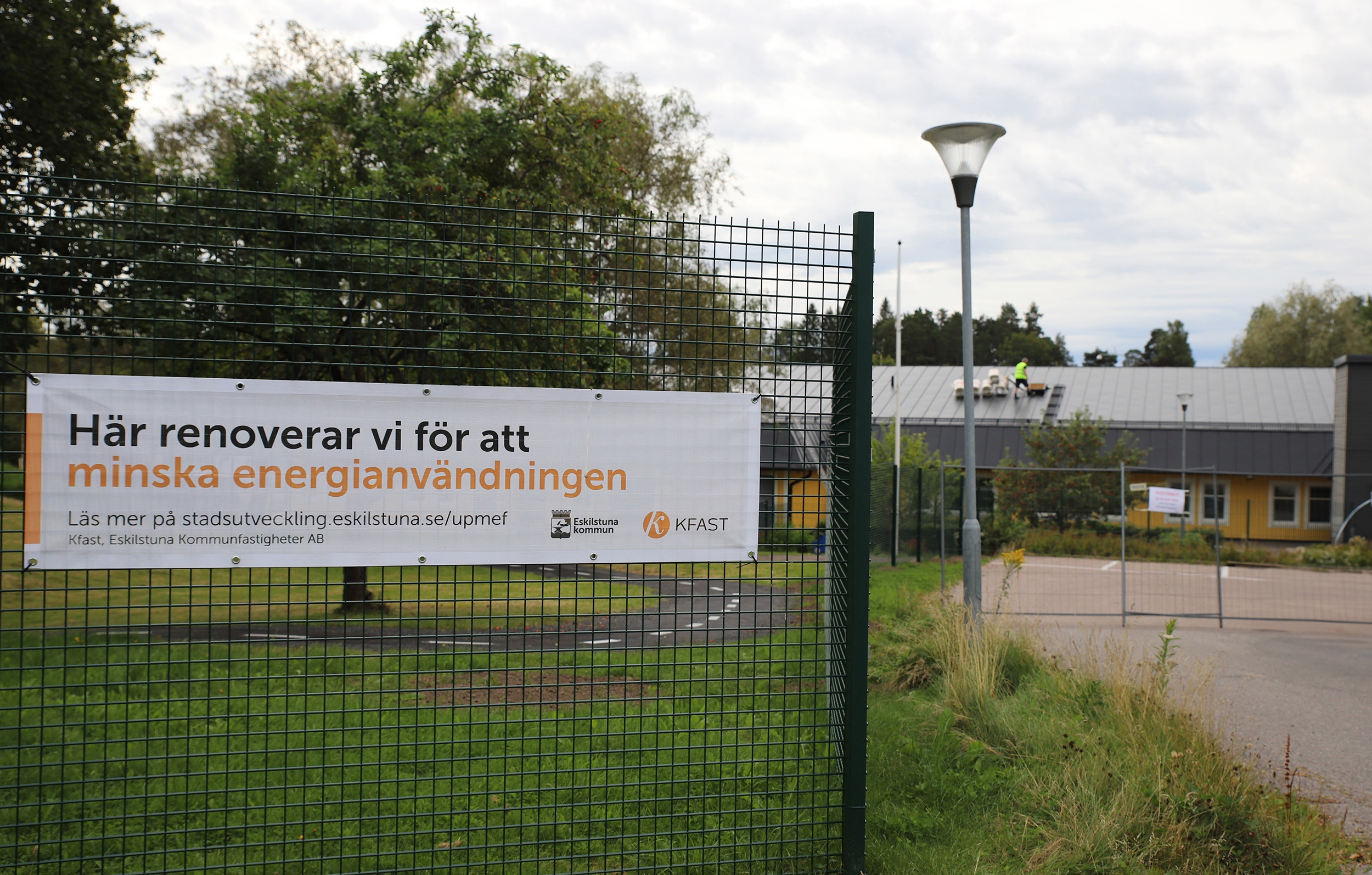 Staket runt förskola med skylt med texten Här renoverar vi för att minska energiförbrukningen.