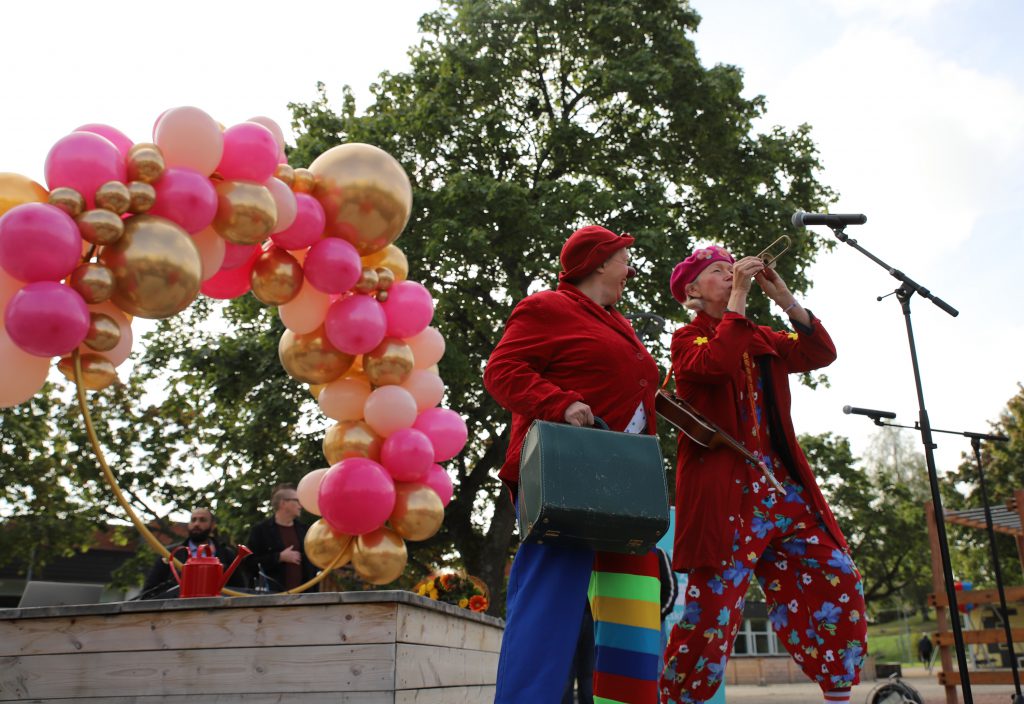 Två clowner står framför en portal med ballonger.