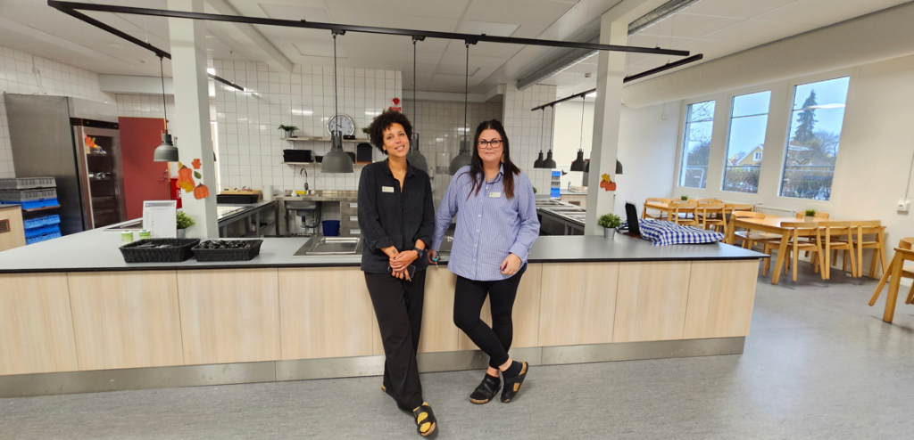 Två kvinnor står i en skolmatsal.