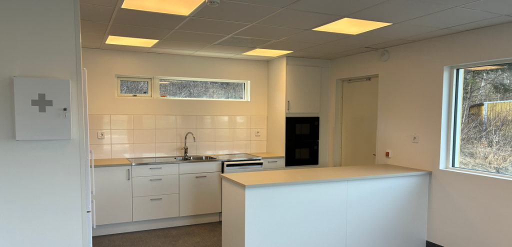 Ett vitt kök med diskho och kylskåp.