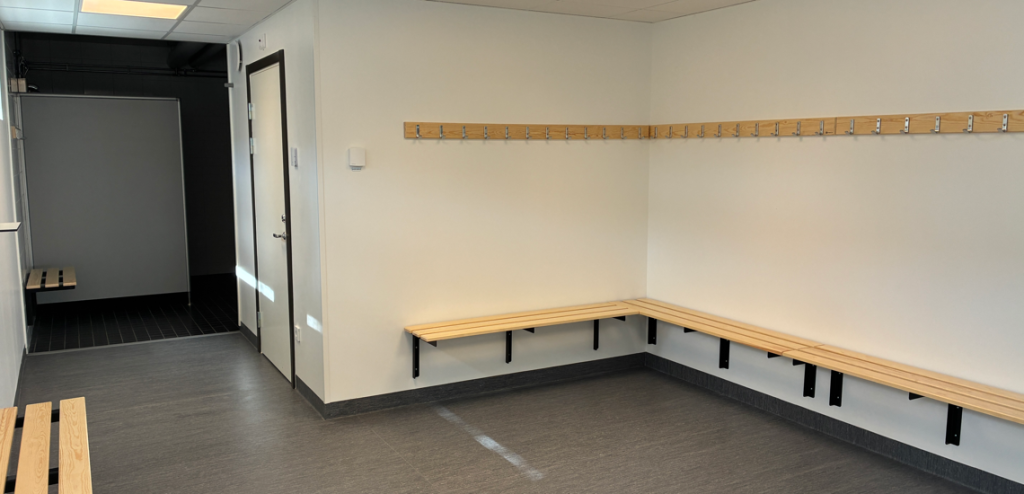 Ett omklädningsrum med bänkar och krokar.