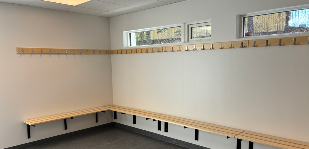 Ett omklädningsrum med en rad träbänkar.