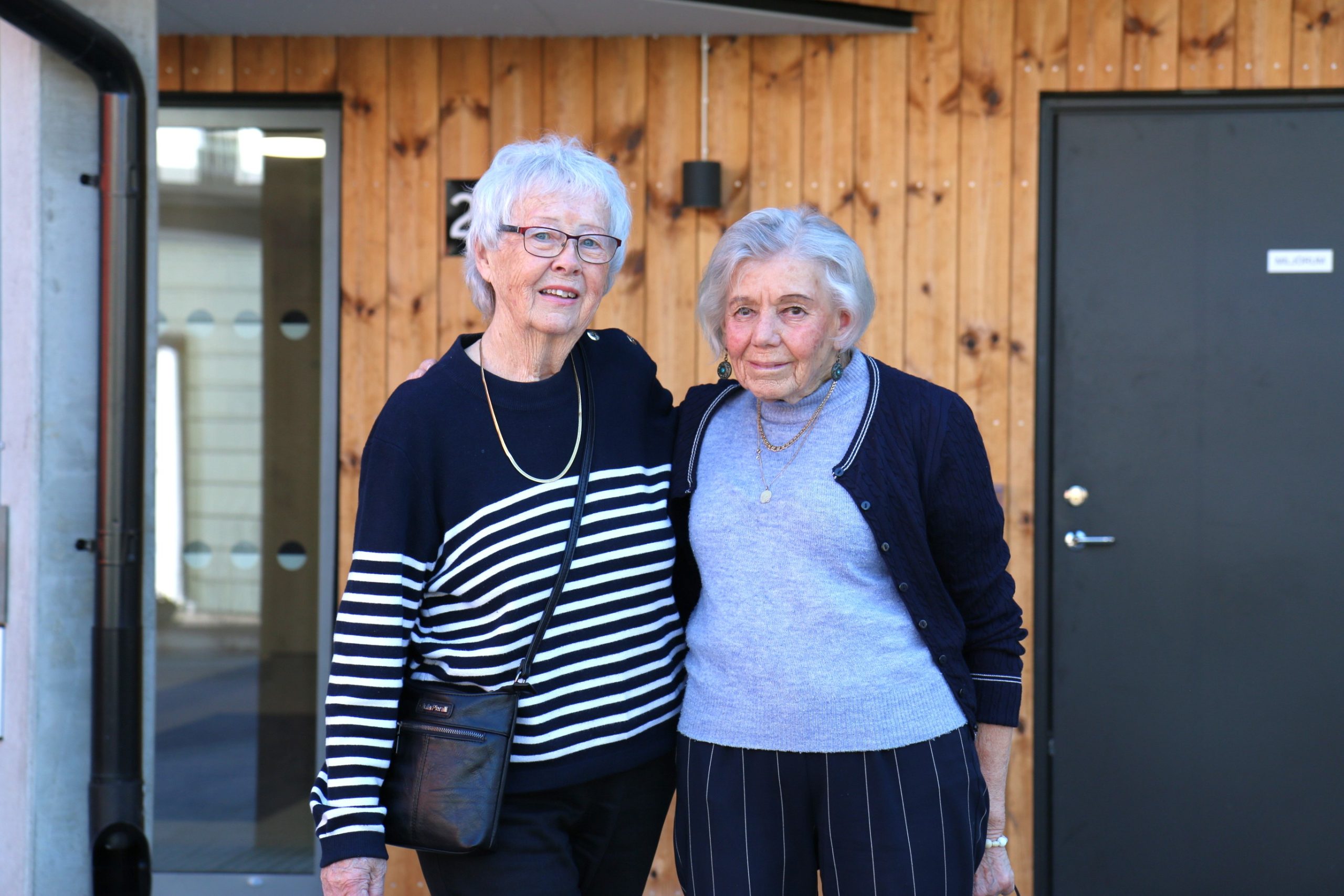 Två damer framför en träfasad