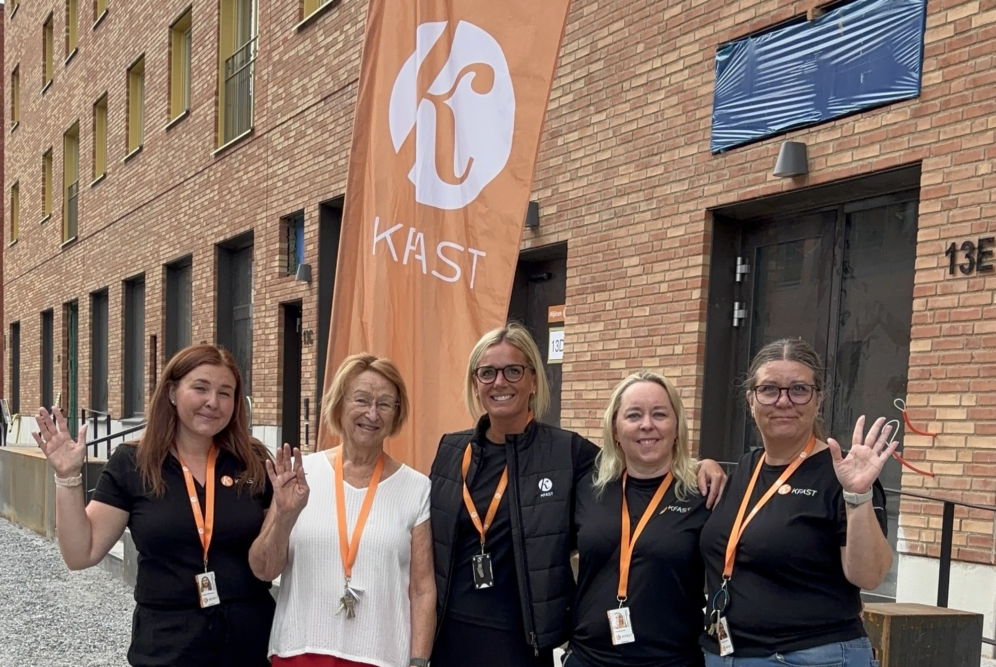 Fem kvinnor står framför Kfast flagga och byggnad