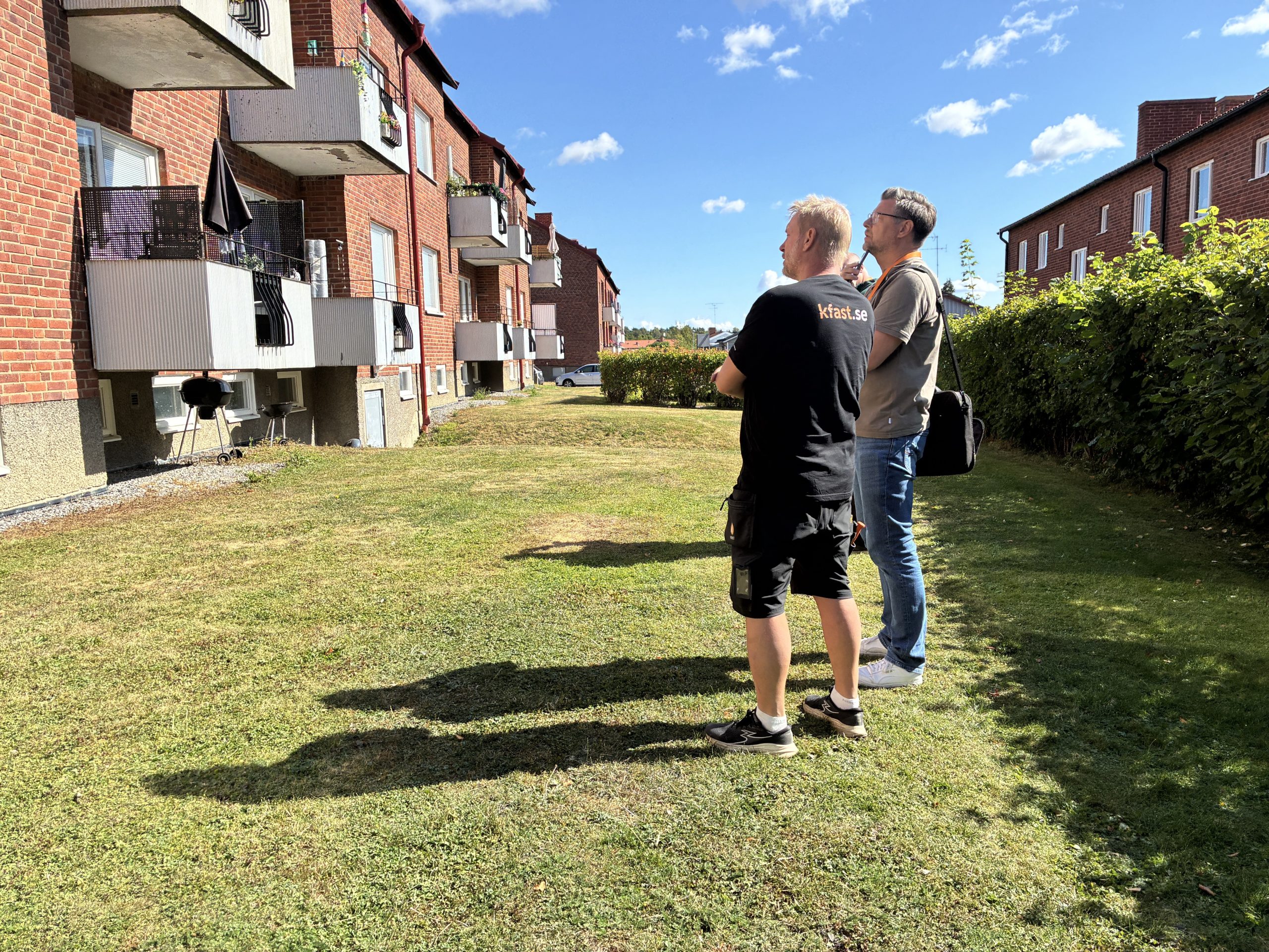 Fastighetsskötare och personal tittar på fasad